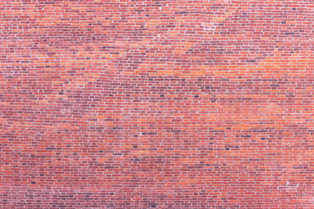 A wall of old, cracked bricks, with a weathered and faded surface. Restored brickwork of an old...