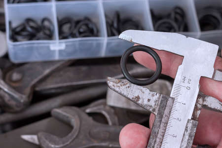 Measuring the diameter of the rubber O-ring with a caliper. An old measuring tool and a set of...