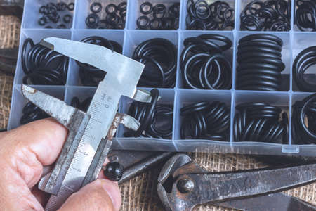 Measuring the diameter of the rubber ring with a caliper. A man is holding an old measuring instrument in his hands.の写真素材