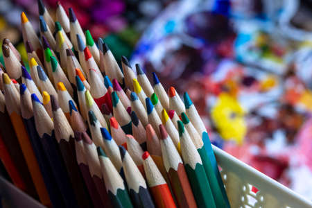 A set of colored pencils in a stand, against the background of art supplies. Pencils on the artist's desk.の写真素材