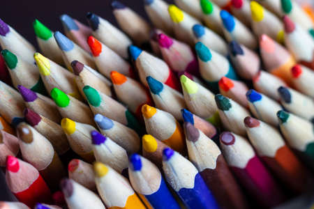A set of colored pencils in a stand, against the background of art supplies. Pencils on the artist's desk.の写真素材