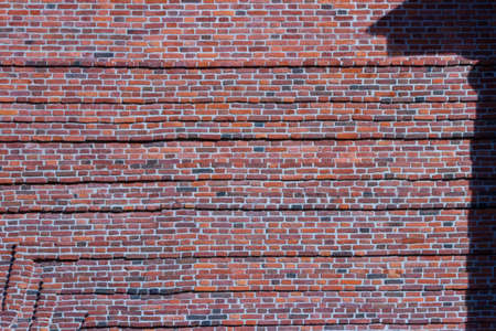 A wide brick blank wall of an old building. Uneven brickwork on a large wall.の写真素材