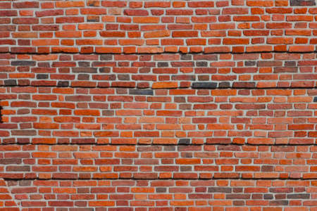A wide brick blank wall of an old building. Uneven brickwork on a large wall.の写真素材