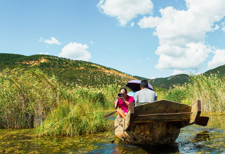 Yunnan, China - August 12, 2018: Tourists on a sight-seeing wooden boat  in Yunnan Province, China.のeditorial素材