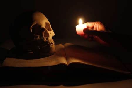 Burning the candle lit the skull and booksの写真素材