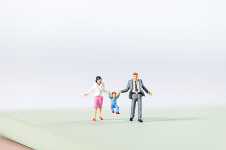 A family of three, father and mother holding the child, jumping happily, miniature peopleの写真素材
