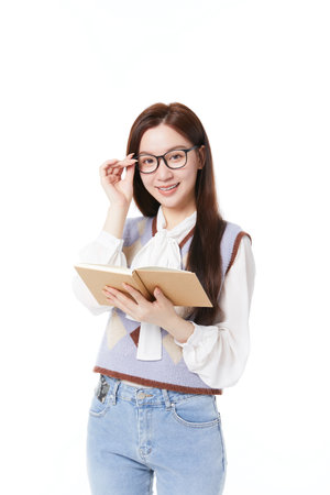 Schoolgirl holding book standing smiling and looking at cameraの写真素材