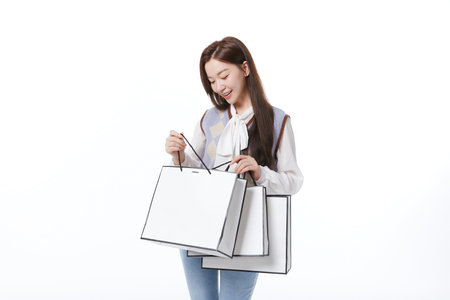 A young woman happily looks at shopping bags in her handsの写真素材