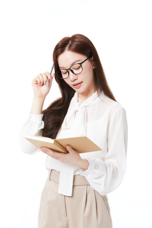 woman in glasses thinking while holding a bookの写真素材