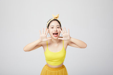 Energetic teenage girl shouting with hands on mouthの写真素材