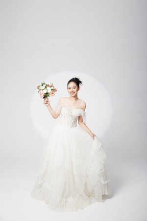 Happy bride in wedding dress holding flowersの写真素材