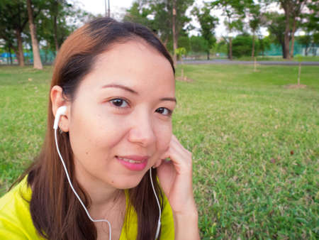 a woman is listening song from smartphone in the parkの写真素材