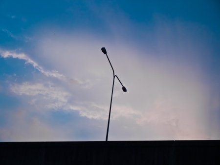 a streetlamp silhouette on the motorway in background blue skyの写真素材
