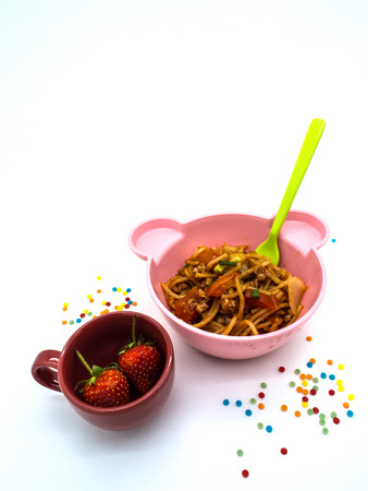 kids menu food set Spaghetti with Tomato Sauce in a pink bear bowl and Strawberries in a cupの写真素材