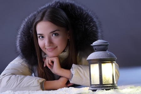beautiful girl on winter snow with lanternの写真素材