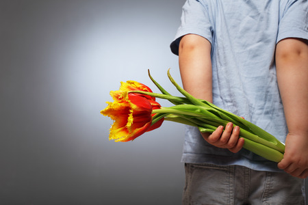 little boy hides behind a flowerの写真素材