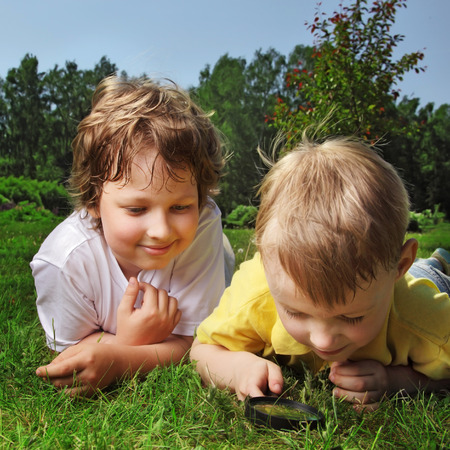 two boys with magnifying glass outdoorsの写真素材