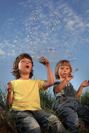 two happy boy blowing bubbles on natureの写真素材