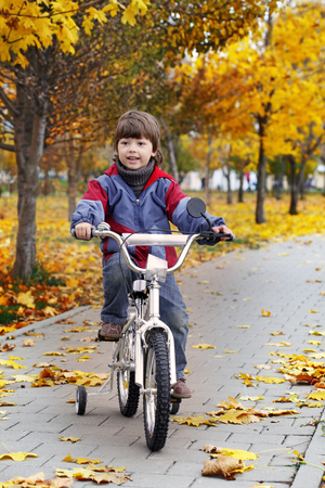 happy boy in autumn park rides his bikeの写真素材