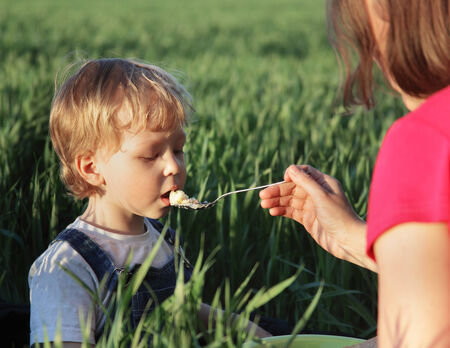 boy with mom eats in natureの写真素材