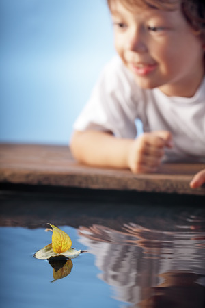 happy boy play in leaf ship (focus on ship)の写真素材