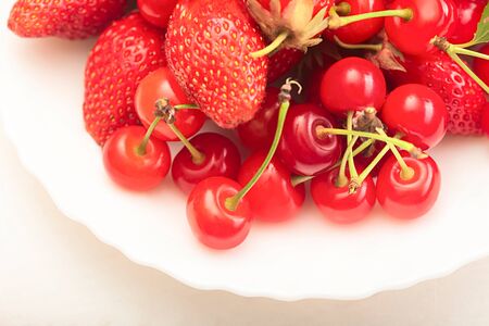 Ripe juicy cherries and berry in plates on the table