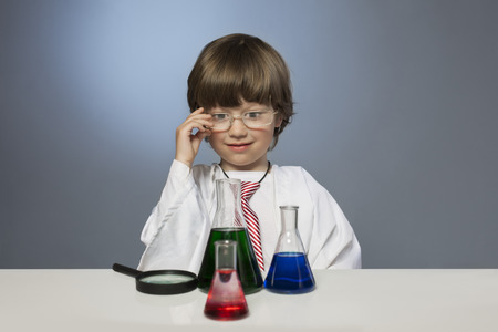 boy studying a substance in a test tube with a magnifying glassの写真素材