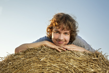 teenager on a haystack in the field in autumnの写真素材