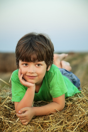 boy in a haystack in the field in autumnの写真素材