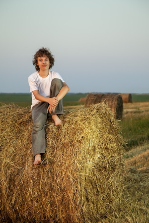 teenager on a haystack in the field in autumnの写真素材
