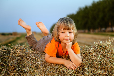boy in a haystack in the field in autumnの写真素材