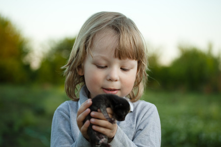 Happy kid with a kitten in her arms in natureの写真素材