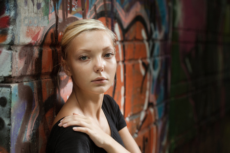 beautiful girl on a city street near a wall of graffitiの写真素材