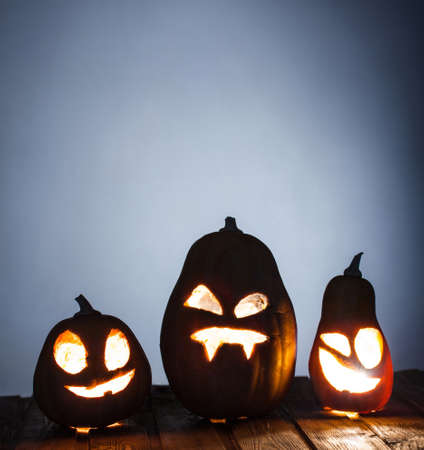 Jack o lanterns Halloween pumpkin face on wooden background and autumn leafsの写真素材