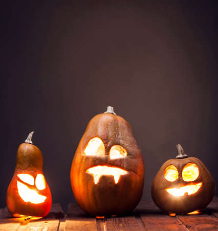 Jack o lanterns Halloween pumpkin face on wooden background and autumn leafsの写真素材