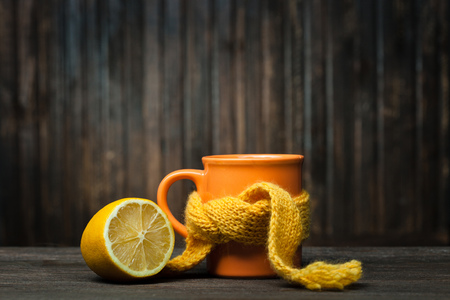 Healing glass of tea in a scarf and a lemon on a wooden backgroundの写真素材