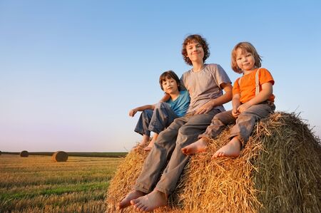 3 boys in a haystack in the field in autumnの写真素材