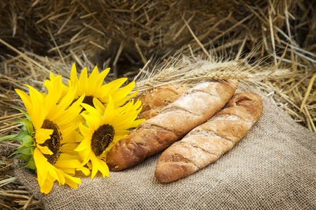 ears of wheat and bread lay on sackcloth in the haystackの写真素材