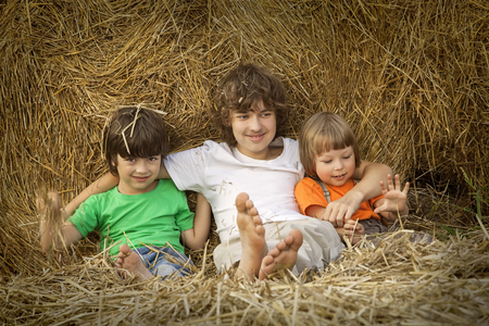 3 boys in a haystack in the field in autumnの写真素材