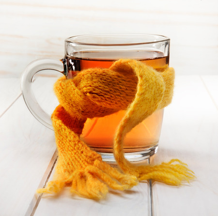 Healing glass of tea in a scarf on a wooden backgroundの写真素材