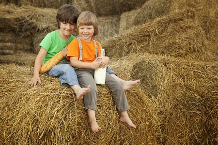 two boy on a haystack with bread and milkの写真素材
