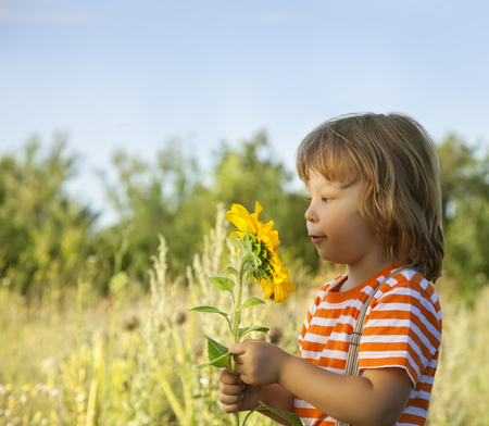 Happy boy with sunflower outdoorsの写真素材