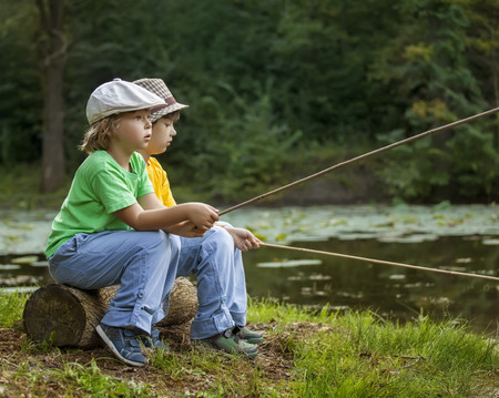 Happy boys go fishing on the river, Two children of the fisherman with a fishing rod on the shore of the lakeの写真素材