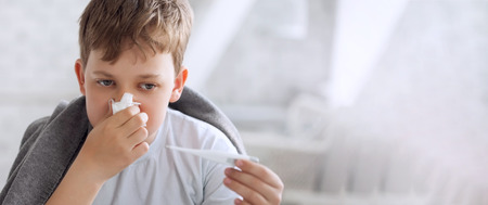 boy wipes his nose with a tissueの写真素材