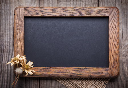 blackboard empty decorated with dried flowers on the old wooden table top viewの写真素材