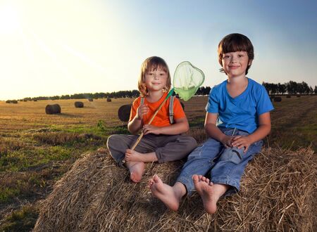 2 boys in a haystack in the field in autumnの写真素材