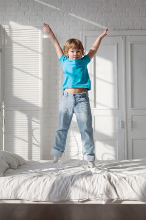 child jumping on the bed in the bedroomの写真素材