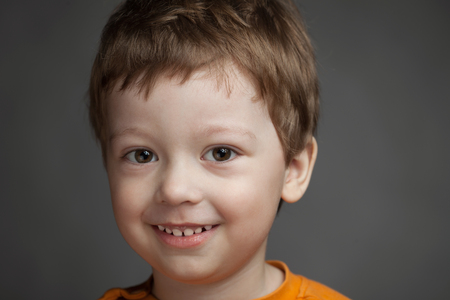 Boy with positive emotions on a gray background, child smiles charming smart studio photo.の写真素材