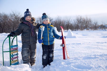 two happy boys on sled and Skis in winter outdoorsの写真素材