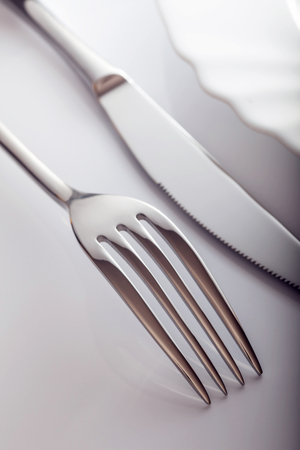 Empty plate with knife and fork on a white background.